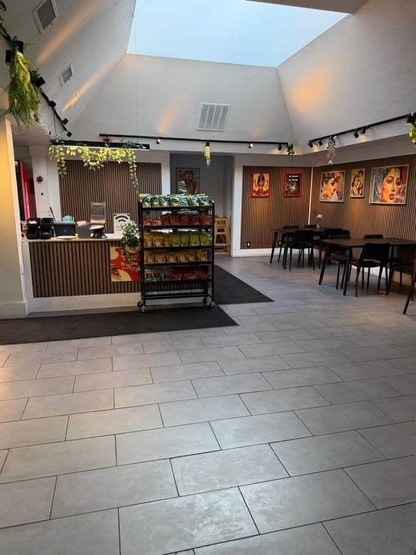 Interior dining room with front counter, snack rack and framed Bollywood portraits under a vaulted skylit ceiling
