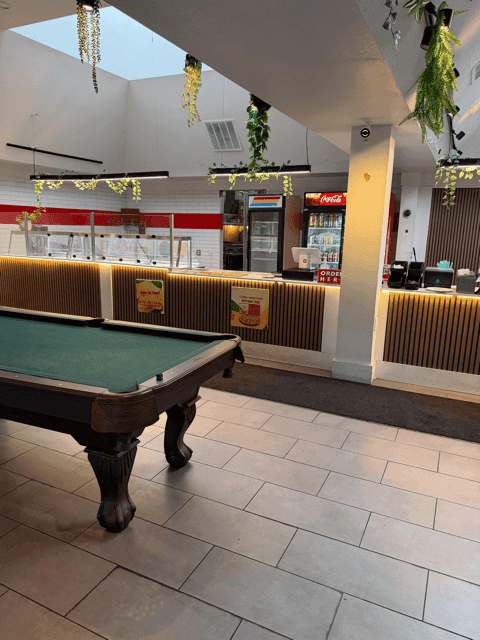 Hot service line with sneeze guards and a stocked beverage cooler behind the pool table